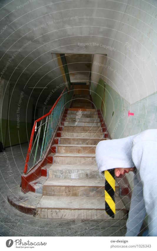 Teenager posing with barrier tape hanging from hood younger youthful Yellow Black Gray Gloomy Stairs Young man cordon Striped Colour photo Construction site