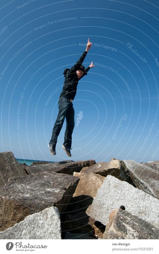 Teenager jumps on the beach of Hiddensee younger Jump Hop stones Blue