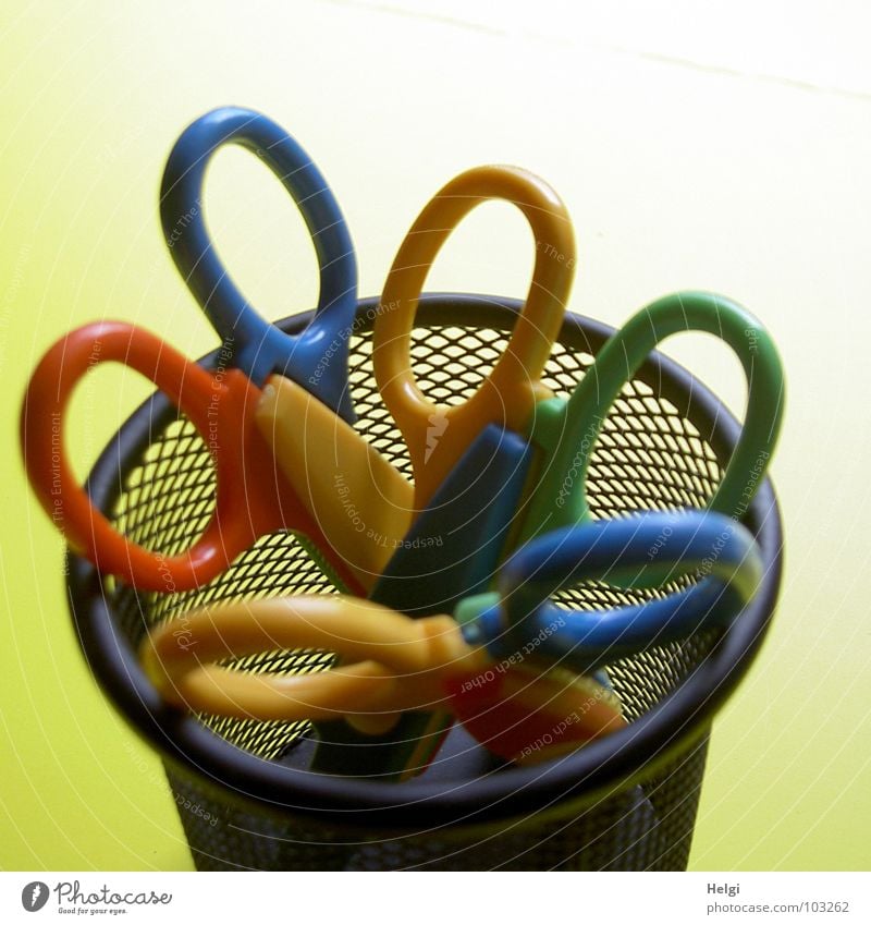 three coloured scissors in a round wire container in front of a yellow background Mug Basket Door handle Cut Edge Vertical Stand Black Reticular Yellow Red