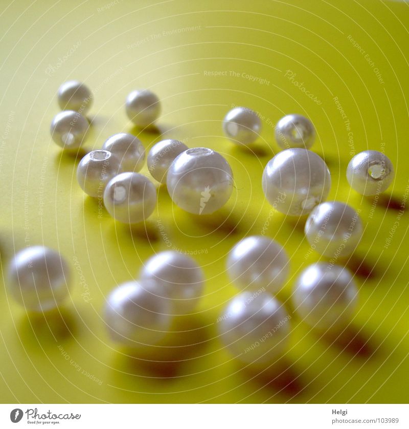 several mother-of-pearl pearls lie on a yellow background Handicraft Embellish Round White Mother-of-pearl Glittering Glimmer Delicate Arrange Light Yellow Dark