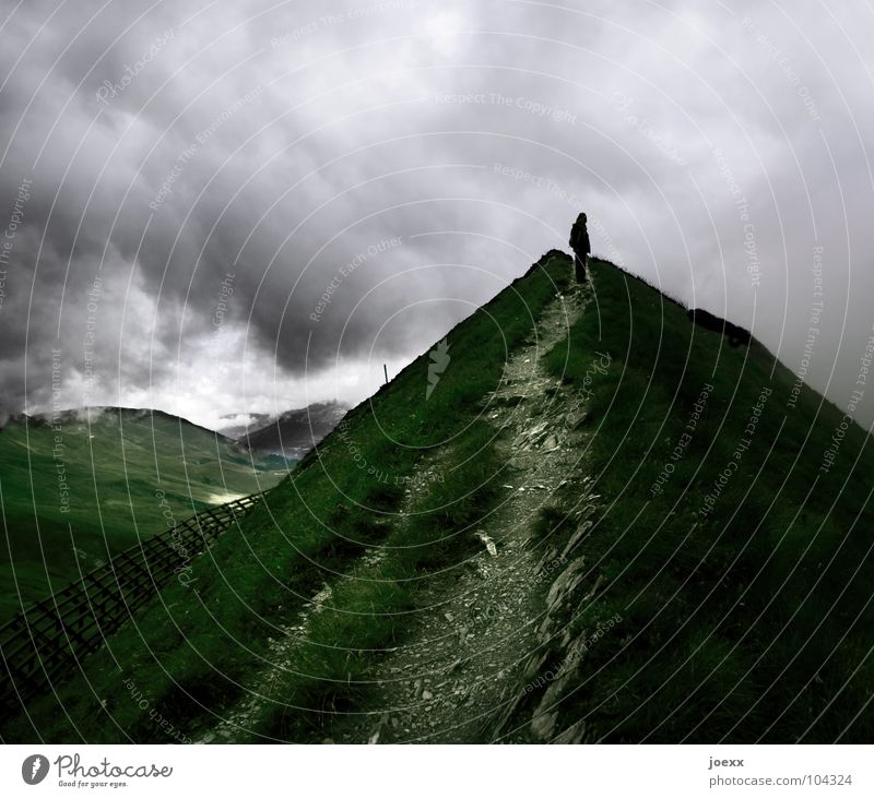Woman standing lonely at end of path on green mountain top, gloomy clouds in sky hikers Man ascension Incline Go up Climber Peak Bad weather Loneliness Success