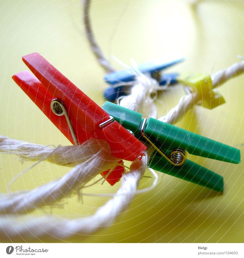 several colorful clothespins clamp on a rope against a yellow background Holder String Packaging tape Clothes peg Wire Attachment To hold on Together
