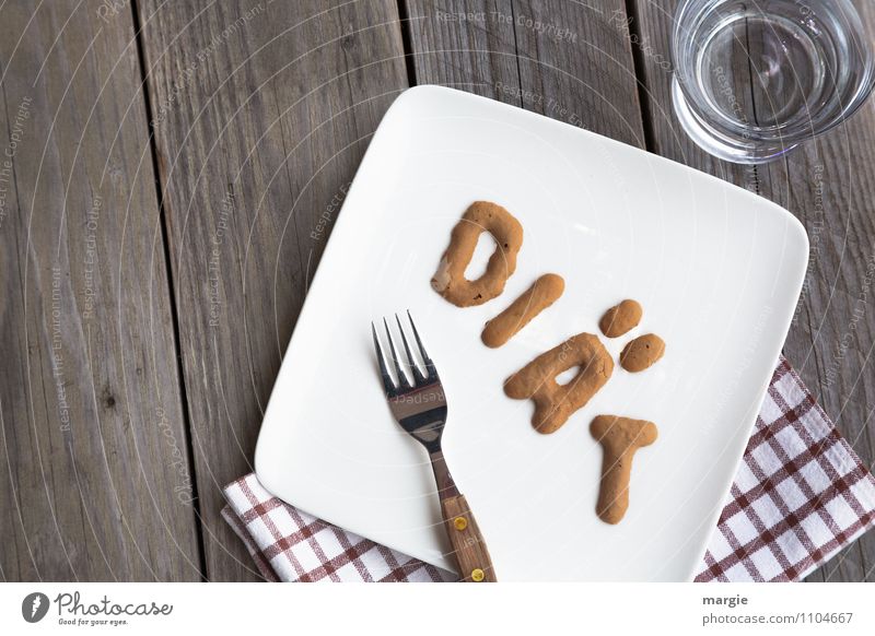 The letters DIÄT on a plate with napkin, fork and a water glass on a rustic wooden table Nutrition Breakfast Lunch Dinner Organic produce Vegetarian diet Diet
