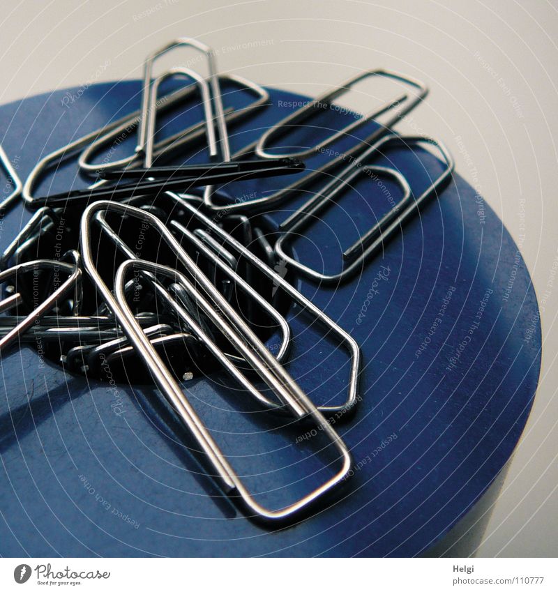 several paperclips magnetically adhere to a container Paper clip Wire Curved Warped Tin Magnet Magnetic Attract Stand Together Side by side Multiple Small White