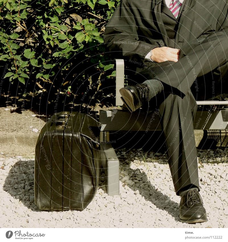 The suit fits Colour photo Subdued colour Exterior shot Business Masculine Man Adults Legs Bushes Train station Traffic infrastructure Suit Tie Bag Footwear Sit