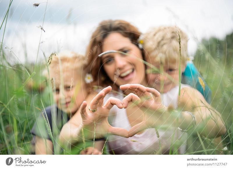 Young mother forms heart with her children in the high grass Joy Leisure and hobbies Playing Trip Freedom Garden Mother's Day Father's Day Parenting Human being