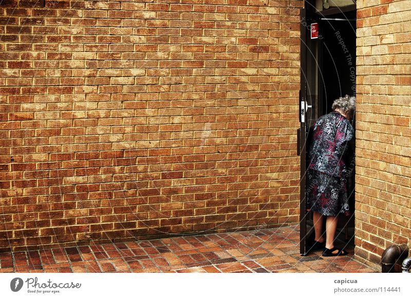 The city is a lonely place Town Grief Distress Woman alone brick old elderly old age grandmother Clothing pipes sad Wall (barrier)