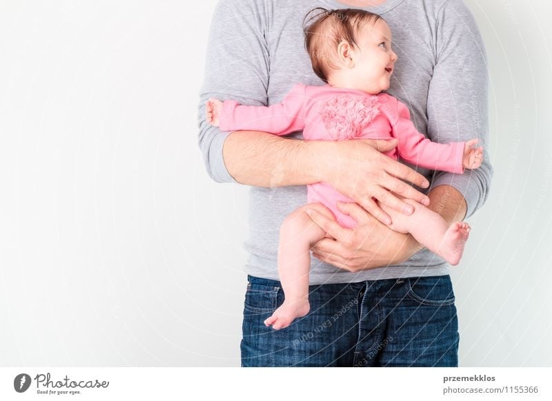 Father holding his smiling daughter. Baby is wearing pink body suit and looking at right side Lifestyle Beautiful Parenting Child Girl Man Adults Infancy 2