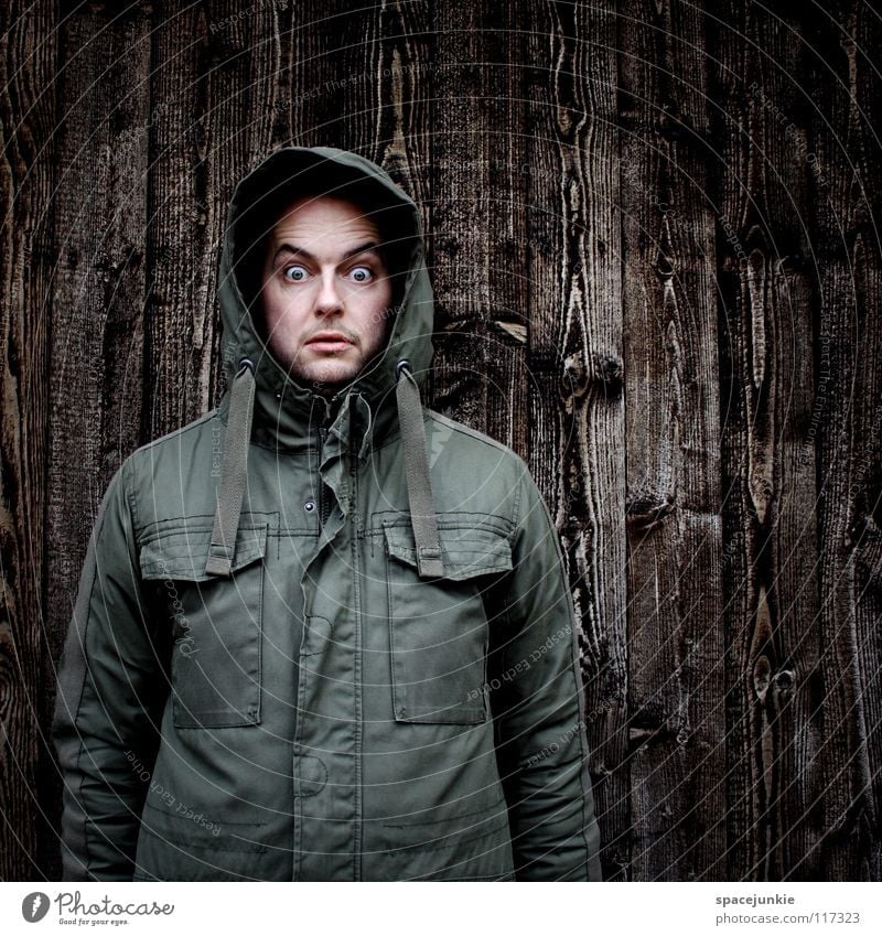 I see something you can't see! Man Portrait photograph Freak Wall (building) Wood Winter Cold Fear Eerie Panic Joy Structures and shapes Hooded (clothing)