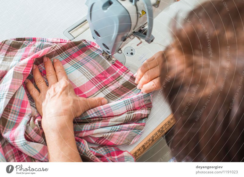 Dressmaker woman sews clothes on sewing machine in factory