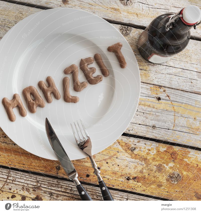 On a rustic wooden table a plate with the letters MAHLZEIT, knife and fork and a bottle of beer Food Nutrition Lunch Dinner Picnic Vegetarian diet Diet