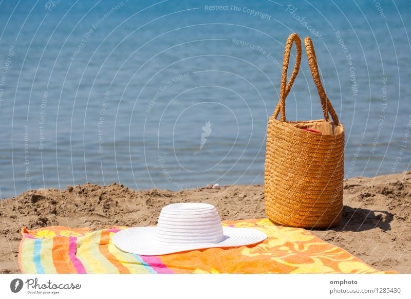 Several beach accessories, bag, hat and color towel put on the sand close to the sea water Relaxation Leisure and hobbies Vacation & Travel Tourism Summer