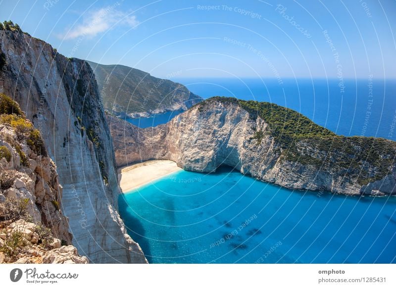 Deserted sunny beach in a sea bay. Panoramic seascape from high position of a beautiful coastal place with deep blue sea water, sun light and wide blue sky.