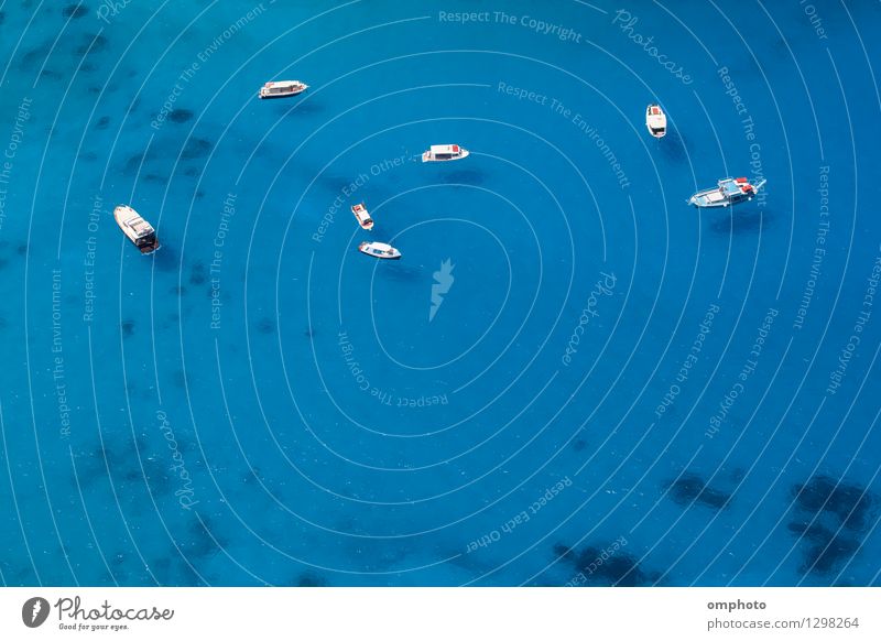 Aerial photo of several boats anchored in a sea bay with shallow clear blue water. The water is clean enough to enable to see the boats shadows on the seabed.