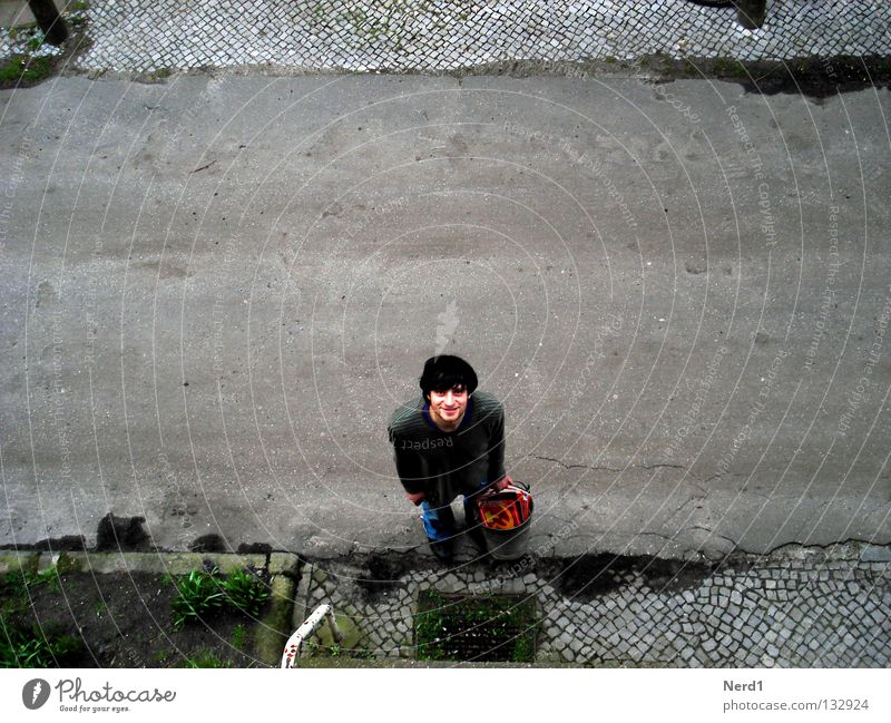 Socialist waste Street Cobblestones Paving stone Man Laughter Bucket Old Derelict Tumbledown Bird's-eye view Exterior shot Upward Copy Space middle Young man