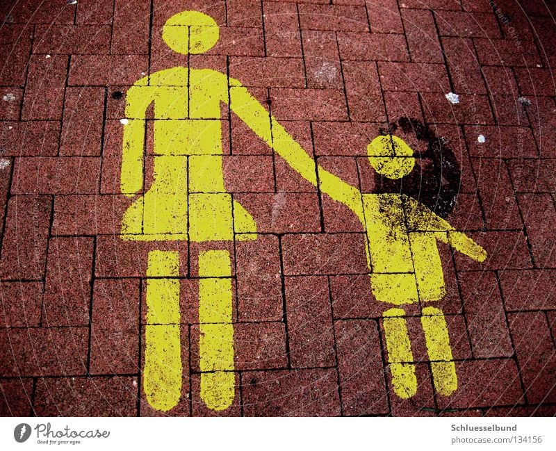 Mother with child Parking Child Adults Arm Legs Traffic infrastructure Stone Dark Yellow Red Black Lane markings Stone floor Parking lot Touch Colour photo