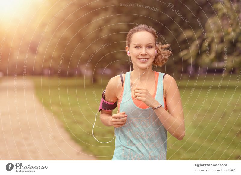 Pretty athletic woman running in a park Lifestyle Happy Summer Music Sports Jogging Woman Adults Landscape Autumn Leaf Park Street Movement Fitness Listening