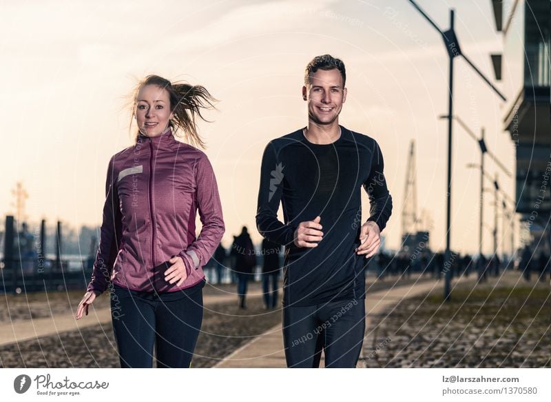 Active young couple jogging side by side in an urban street Lifestyle Happy Face Sports Success Jogging Woman Adults Man Couple 2 Human being 18 - 30 years