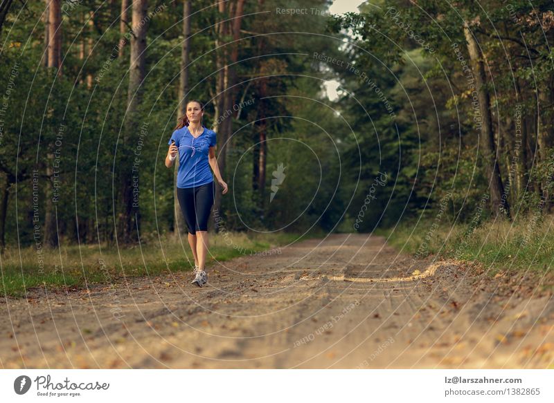 Athletic woman out jogging in a forest Lifestyle Body Music Sports Jogging Technology Girl Woman Adults 1 Human being 13 - 18 years Youth (Young adults) Nature
