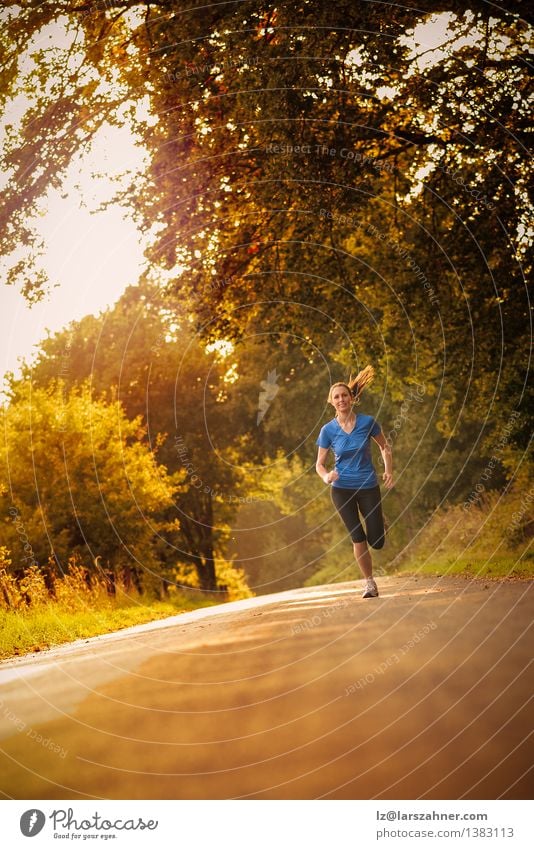 Sporty woman running on a country road Happy Sports Jogging Woman Adults 1 Human being 13 - 18 years Youth (Young adults) Landscape Autumn Tree Leaf Park Street