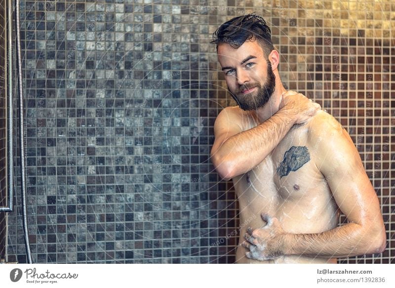 Friendly young man soaping himself in the shower Skin Face Wellness Bathroom Man Adults Beard Smiling Wet Clean at camera bath bathing care Caucasian chest