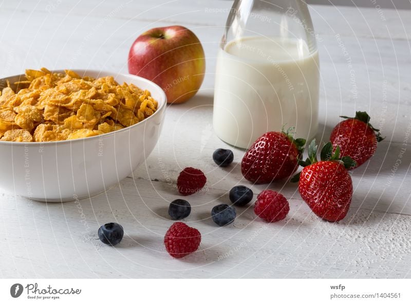 Pouring milk in a cereal bowl on a blue background. Cornflakes and