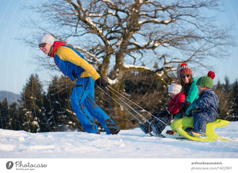 Young sporty couple with children at the sledge in winter in sunshine Joy Leisure and hobbies Sleigh Vacation & Travel Tourism Winter Winter vacation