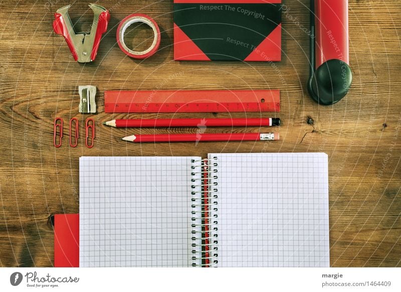 Landscape format: Red and black desk utensils on a wooden table. notebook, pencils, ruler, adhesive tape, sharpener, paper clips, book, stapler, staple monkey