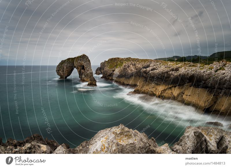 pierced rock Landscape Water Sky Clouds Horizon Weather Bad weather Rock Waves Coast Fjord Ocean Deserted Fantastic Gigantic Brown Green White Cliff