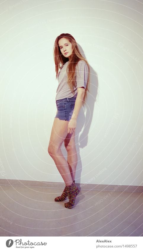 Girl stands sideways, smiling in the camera, long legs, wears