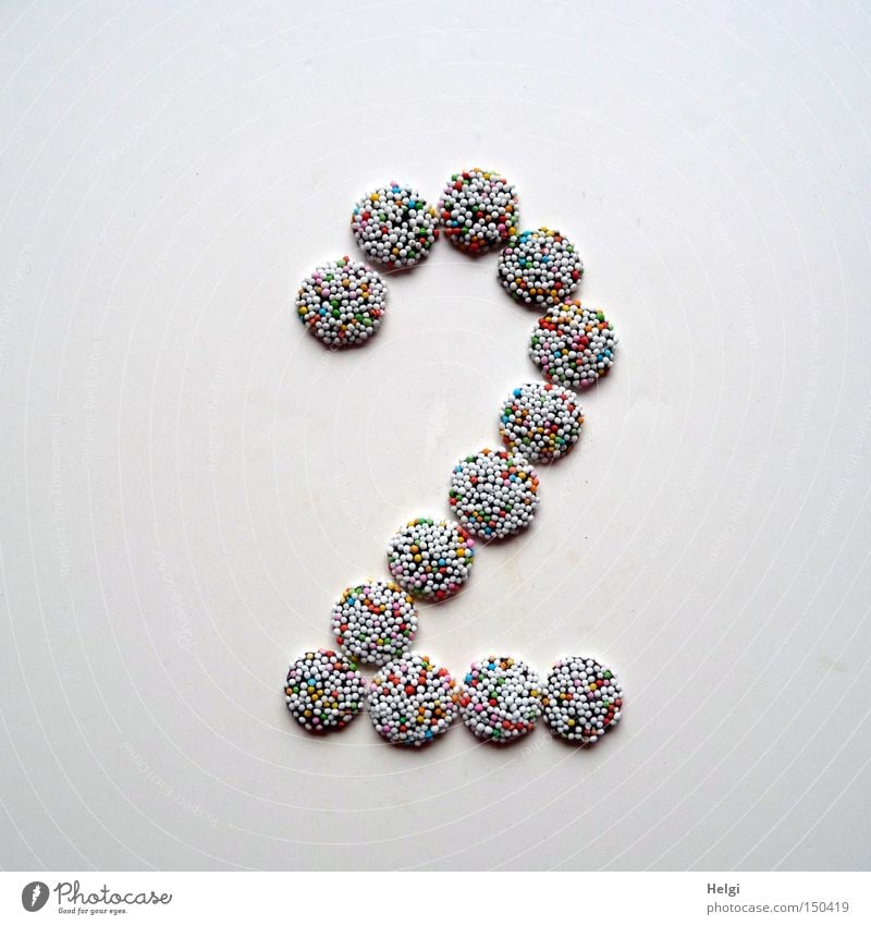 Number 2 laid out of small chocolate candies with colored sugar sprinkles on white background Digits and numbers Advent Calendar Candy Chocolate Granules