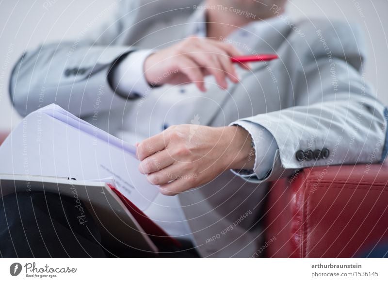 Businessman in a suit with documents in his hand on a red couch Professional training Academic studies Study Office work Workplace Economy Services