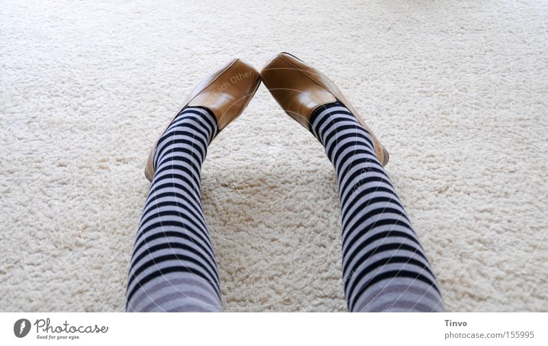 A girl with colorful striped stockings stands on the shadow of a