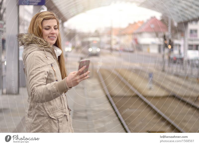 Young woman with mobile phone at train station Happy Vacation & Travel Winter Telephone Woman Adults 1 Human being 18 - 30 years Youth (Young adults) Transport