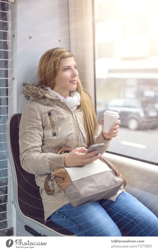 Blond woman sitting on commuter train Coffee Lifestyle Happy Beautiful Winter Telephone Woman Adults 1 Human being 18 - 30 years Youth (Young adults) Transport
