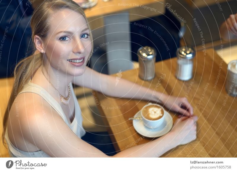 Smiling blond woman sitting in a bar with a cappuccino Coffee Lifestyle Beautiful Relaxation Table Feminine Woman Adults 1 Human being 18 - 30 years