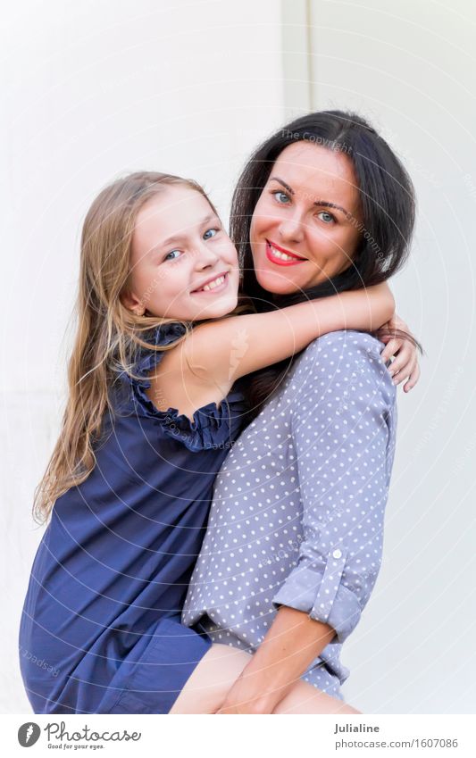 Embracing brunette mother and blond daughter Child Schoolchild Girl Woman Adults Parents Mother Infancy 2 Human being 3 - 8 years 8 - 13 years 18 - 30 years