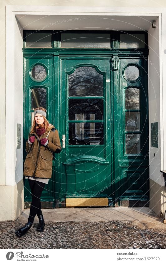 Young woman standing in front of green front door Lifestyle Contentment Winter Human being Feminine Youth (Young adults) 1 18 - 30 years Adults Town