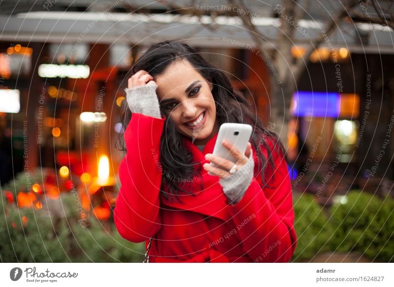 Beautiful Smiling Woman in red coat with mobile phone in hands, smartphone, urban scene woman smile smiling lifestyle girl person cold winter female technology