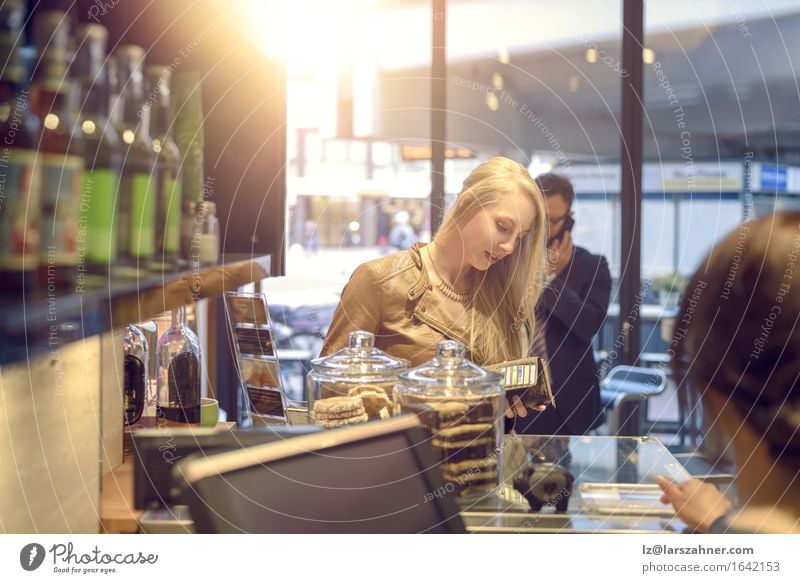 Attractive blond woman paying in a shop Shopping Happy Woman Adults Blonde Paying attractive Bank note bar Cafeteria Cashier Copy Space counter Customer
