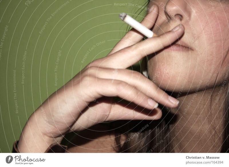 Young woman with a cigarette in front of a green background Colour photo Subdued colour Interior shot Close-up Copy Space left Copy Space top Neutral Background