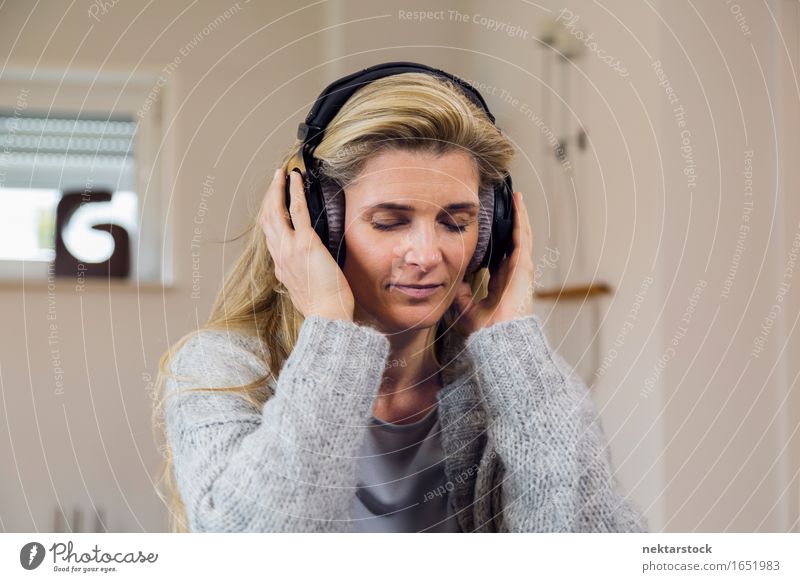 Pretty blonde woman listening to music on couch at home Happy Contentment Relaxation Leisure and hobbies Entertainment Music Woman Adults Blonde Listening