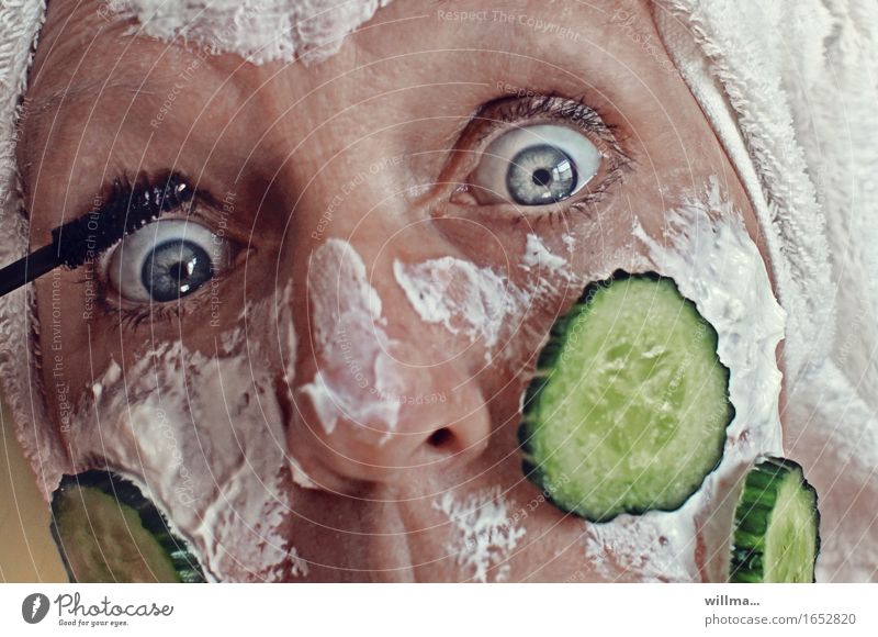 Woman with quark mask and cucumber slices on her face is putting on make-up pretty Skin Face Cosmetics Cream Make-up Mascara Slices of cucumber Feminine Adults
