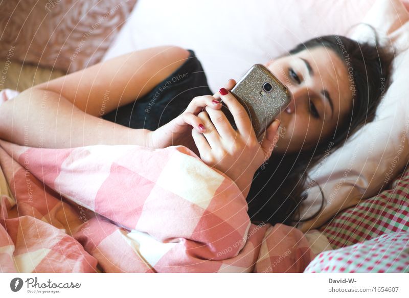 young woman lies in bed and looks at her smartphone Cellphone Bed Youth (Young adults) Woman Lovesickness Write Typing concentrated hollowed
