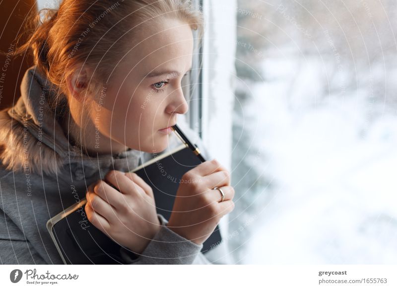 Young girl is dreaming by the window with notebook and pen Face Winter Flat (apartment) Student University & College student Office Business Human being Girl