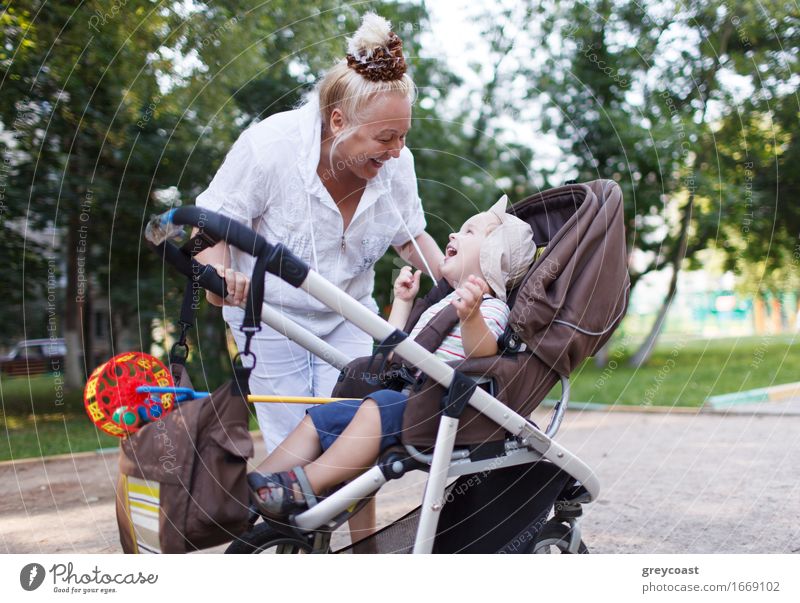 Granny playing with her grandson in a baby stroller in the yard. Lifestyle Joy Happy Beautiful Playing Garden Child Human being Baby Boy (child) Woman Adults