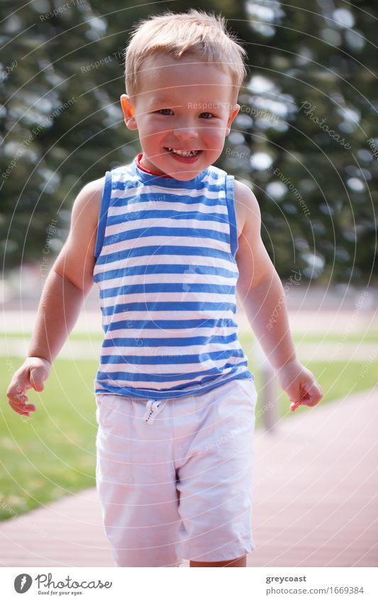Portrait of smiling happy 3 year old boy in striped vest running in the city park and looking to the photographer Lifestyle Joy Happy Beautiful Face