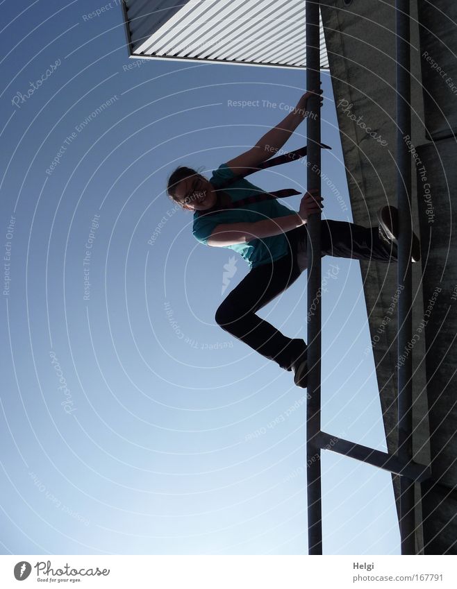 young woman climbs a railing in front of a blue sky Colour photo Subdued colour Exterior shot Copy Space left Copy Space bottom Day Shadow Silhouette Back-light