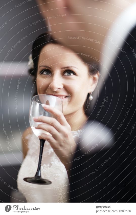 Elegant young woman in a white dress drinking white wine at a function and smiling up at her male partner Alcoholic drinks Champagne Happy Beautiful