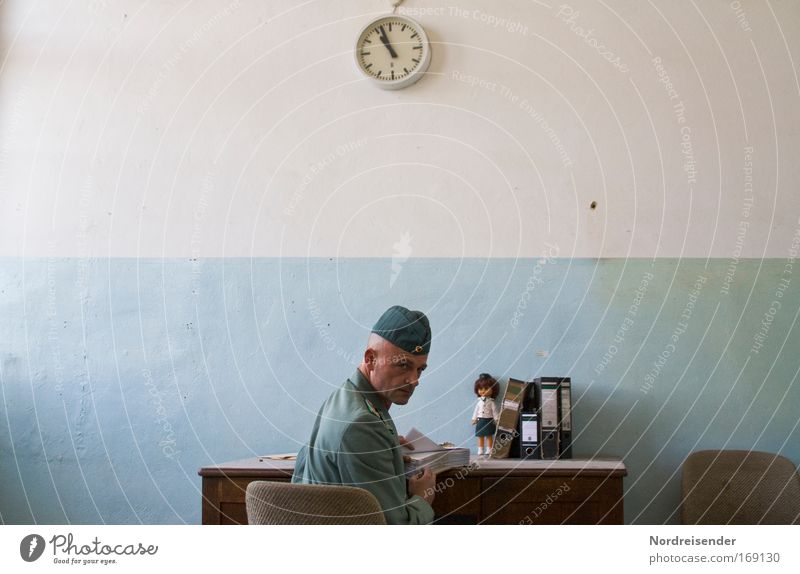 Man in uniform at his desk looking over his shoulder Office work office Career Clock Human being Adults cap File Doll Sign Work and employment Observe Write Sit